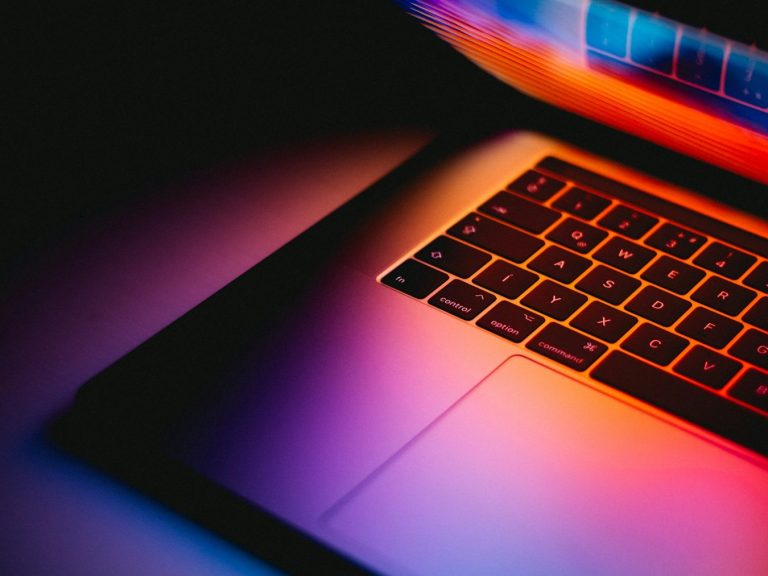 Ein Laptop mit leuchtender Tastatur und farbigem Hintergrund.